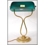 A vintage bankers lamp having a green glass shade raised on a round stepped base with curved brass