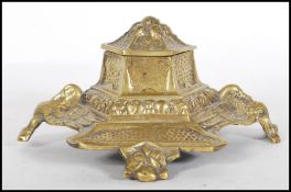 An early 20th Century cast brass inkwell of stepped hexagonal form decorated with birds and floral