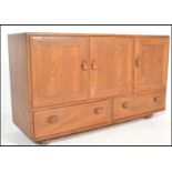 A mid century beech and elm Ercol Windsor pattern sideboard dresser. Raised on ball castors having