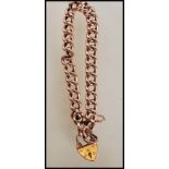 A hallmarked 9ct gold curb link heart padlock bracelet with a safety chain. Hallmarked Birmingham