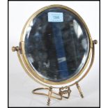 A 20th Century brass bevelled edge swing mirror of circular form raised on adjustable easel stand.