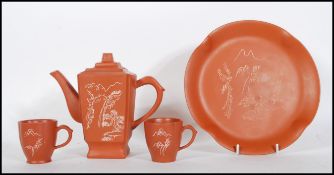 A 20th Century Chinese red clay Yixing tea for two service consisting of square teapot and two