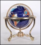 A vintage style lapis lazuli desk top globe having brass mounts with inset semi precious stones.