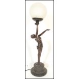 A Art Deco style table lamp in the form of a reclining nude lady holding a frosted glass ball