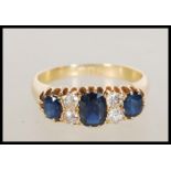 A hallmarked 18ct gold ring set with three sapphires and four round cut diamonds. Hallmarked