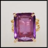 A 9ct gold and amethyst dress ring. The large facet cut rectangular amethyst being 4 prong mounted