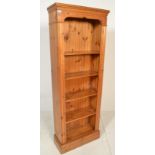 An antique style country pine upright bookcase cabinet. Raised on a plinth base with central bank of