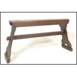 A early 20th Century stained pine bench raised on shaped supports united by a pegged stretcher below