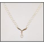 A 9ct gold and cultured pearl necklace and pendant. The sweeping wing pendant with drop pearl set to