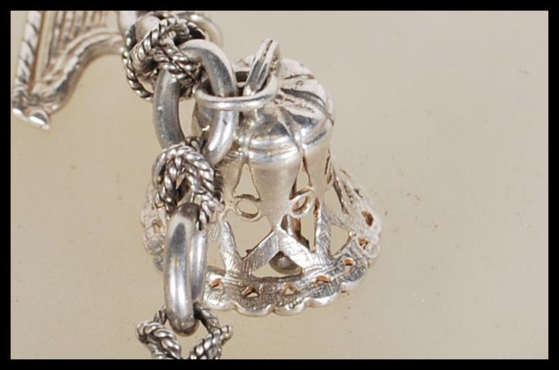 A silver charm bracelet having musical instrument charms to include trumpets, harp, bell violin, - Image 5 of 9