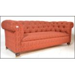 A Victorian  style Chesterfield sofa settee being raised on mahogany turned legs with brass