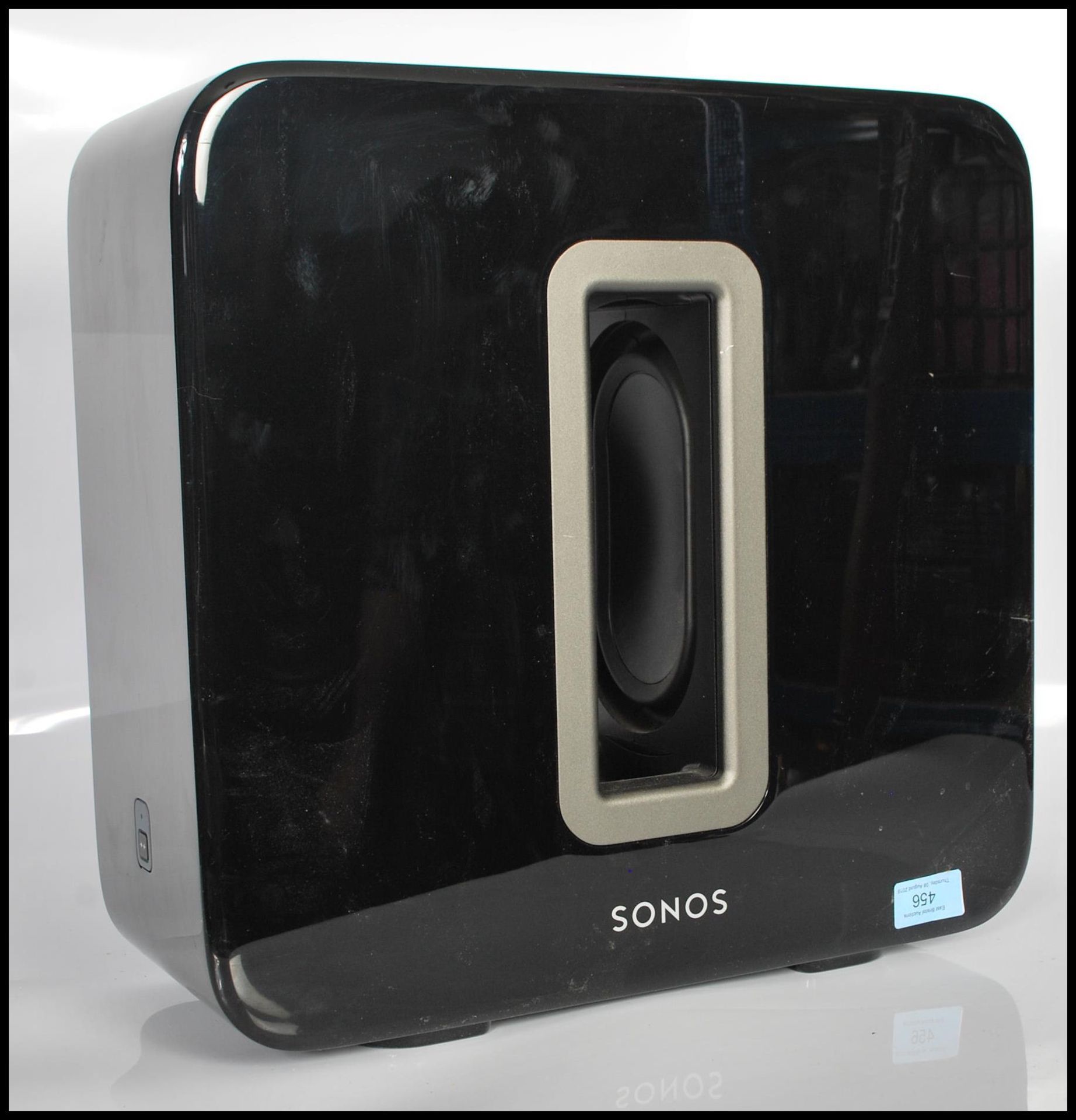 A contemporary Sonos Sub subwoofer bass speaker in black having a polished finish. Power cables