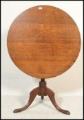 An 18th century Georgian country oak tilt top table. Raised on splayed legs with turned column