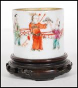 A 19th Century Chinese ceramic cup being hand decorated with children playing with leaves and a bird