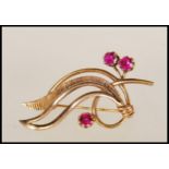 A 9ct gold and red stone hallmarked brooch of Art Nouveau form having 3 claw mounted stones, pin