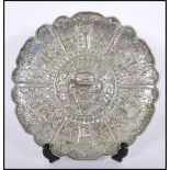 A vintage silvered brass wall charger plate having repousse decoration, central cartouche with