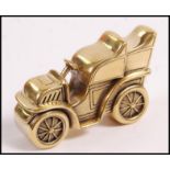 A brass vesta case in the form of a vintage car having a match striker to underneath. Measures 4.2cm