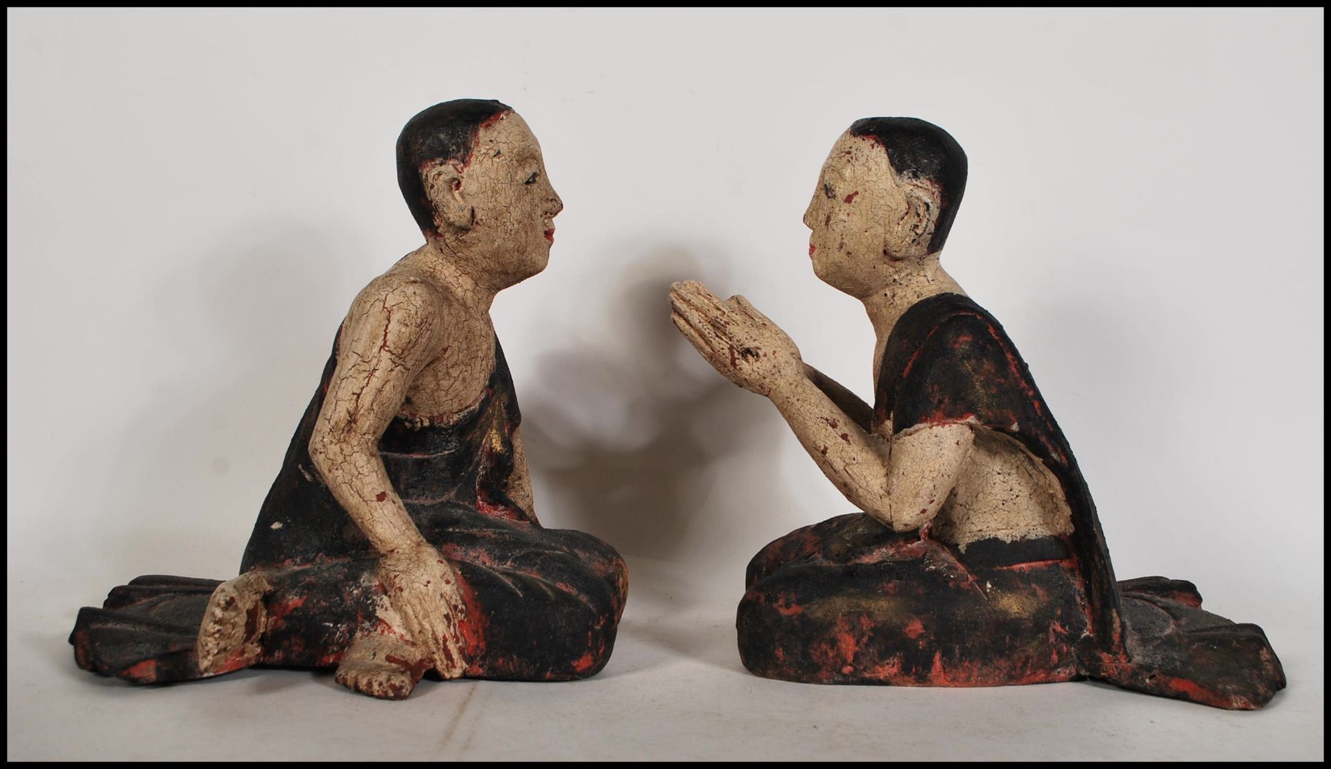 A pair of 20th Century wooden praying Buddhist Monks both in a seated kneeling position having
