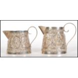 A pair of 20th Century South East Asian silver jugs of tapering form having embossed decoration of