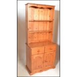 A 20th Century antique style pine Welsh dresser. The dresser having an open shelved upright