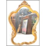 A 20th Century gilt rococo style wall mirror having a symmetrical reeded gilt frame with scrolled