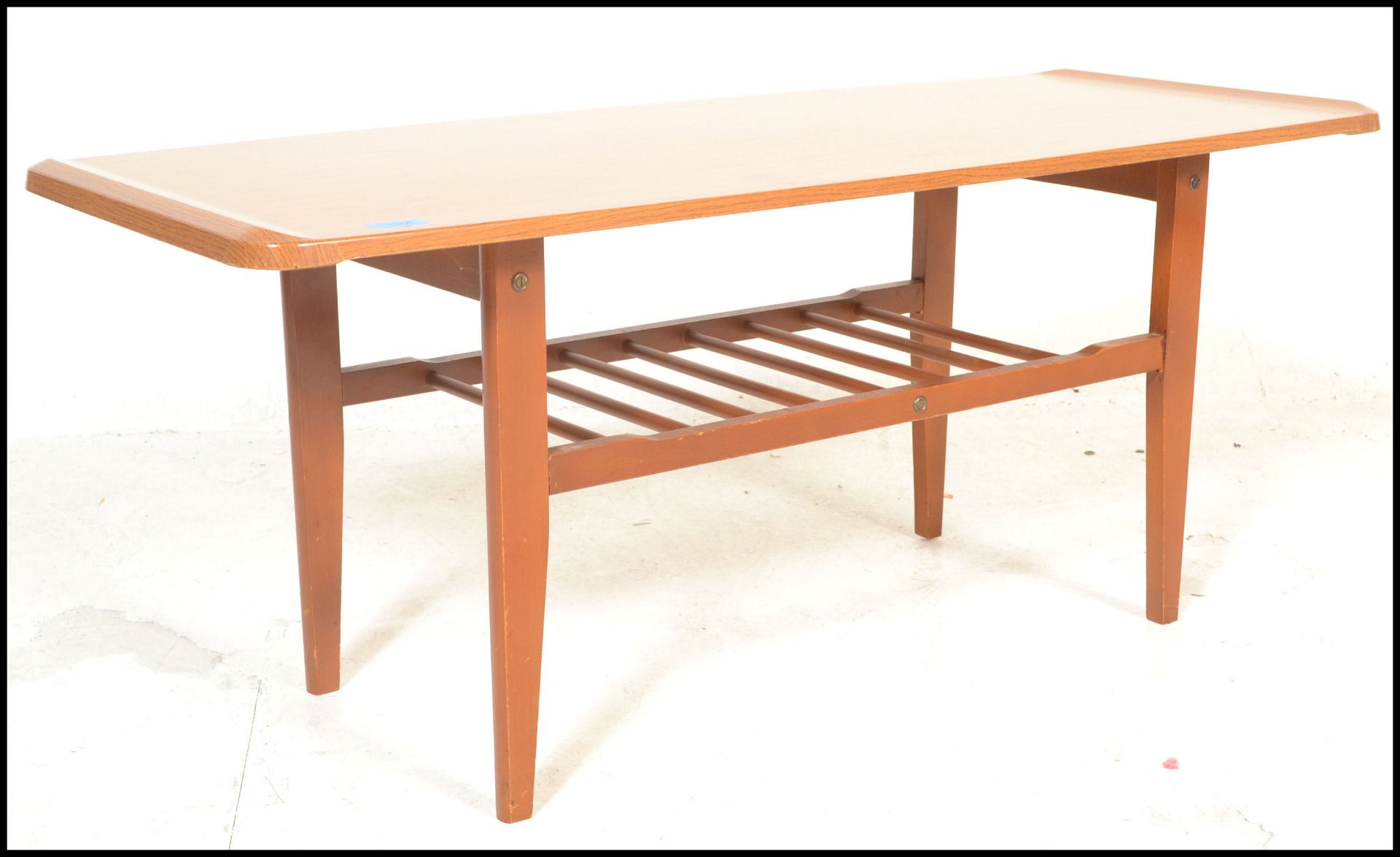 A mid century Danish influence faux teak wood long john coffee table being raised on tapering legs