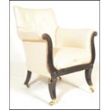 A 19th century Regency ebonised library armchair raised on sabre legs with brass cap castors