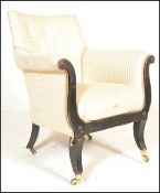 A 19th century Regency ebonised library armchair raised on sabre legs with brass cap castors