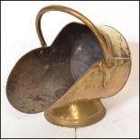 A 19th Century Victorian brass coal scuttle of helmet form raised on conical pedestal base with