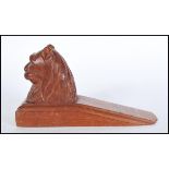 A 20th Century carved wooden door stop in the form of a seated lion. Measures 10 cm x 9 cm.