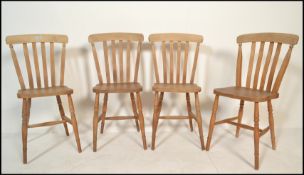 A group of four 20th Century beech and elm wooden dining chairs having rail back back rests raised