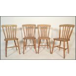 A group of four 20th Century beech and elm wooden dining chairs having rail back back rests raised