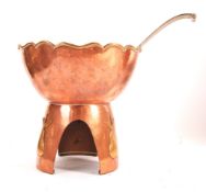 An arts and crafts period copper and brass punch bowl / table top pear poacher raised on a tripod