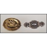 Two 19th Century Victorian mourning brooches to include a yellow metal oval forn brooch decorated