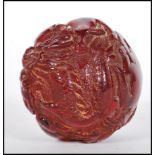A 20th Century Chinese deep red resin sphere decorated with raised animals including a four toed