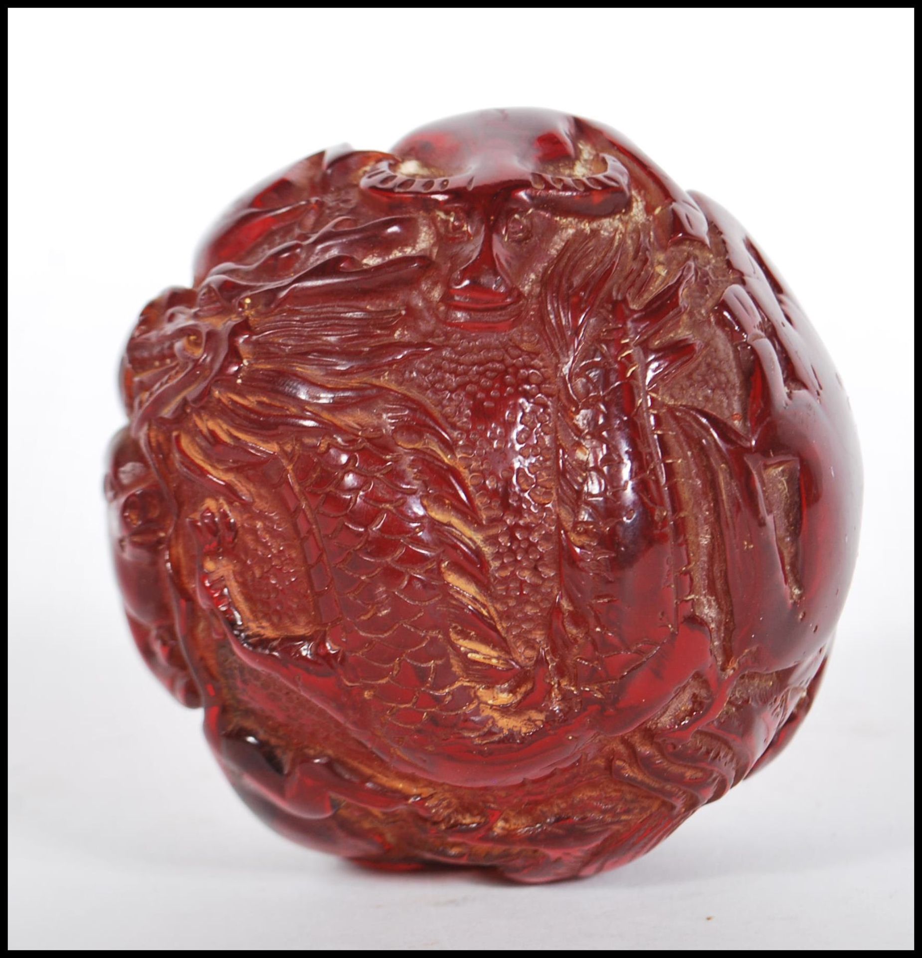 A 20th Century Chinese deep red resin sphere decorated with raised animals including a four toed