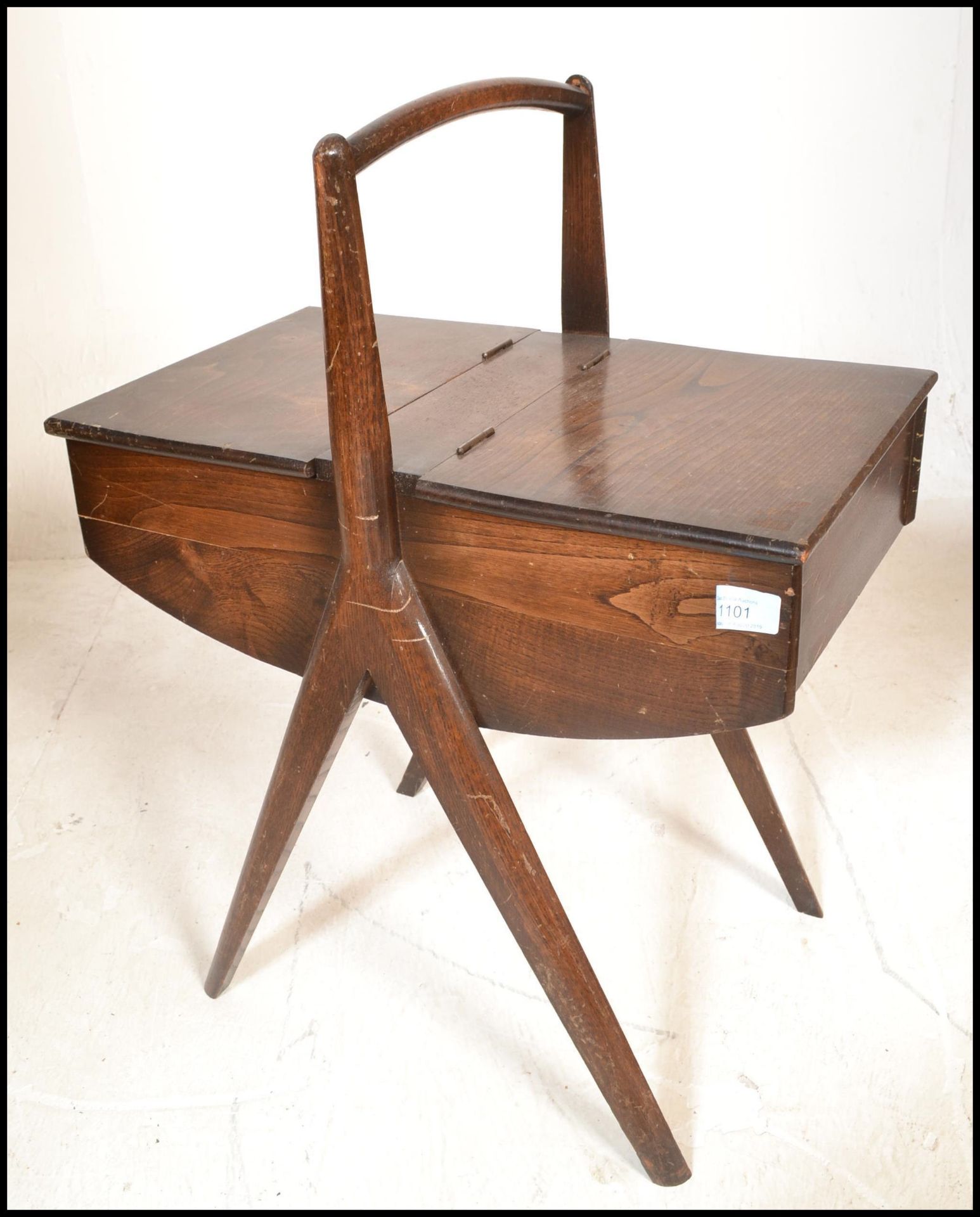 A vintage 20th Century wooden sewing box raised central angular legs with domed handle to the top