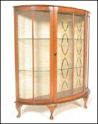 A mid 20th Century bow front mahogany Queen Anne revival display cabinet having glazed panels to the
