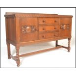 An early/ mid 20th Century oak sideboard having a central bank of three drawers with turned knob