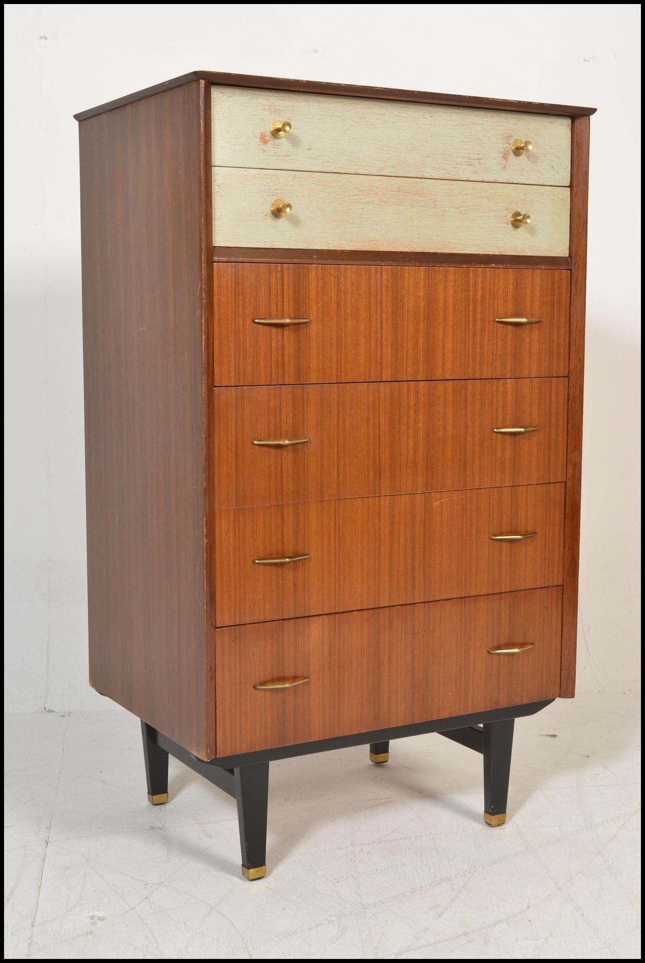 A mid 20th Century retro G-Plan style chest of drawers raised on ebony tapering square legs with