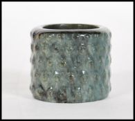 A early 20th Century Chinese mottled dark green jade archer's thumb ring, having ribbed nobly