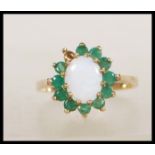 A hallmarked 9ct gold ring set with a central opal cabochon with a halo of green stones.