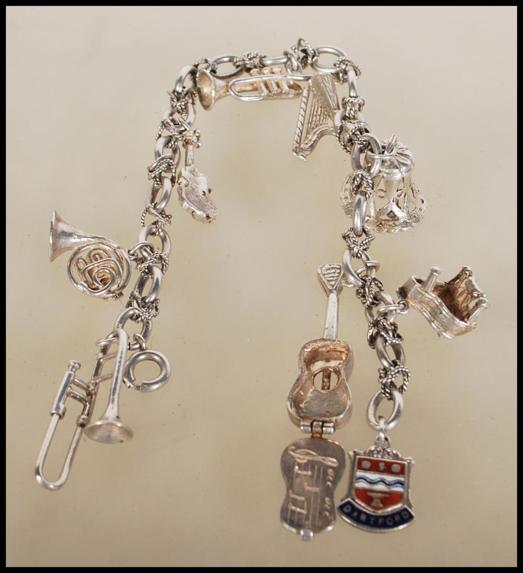 A silver charm bracelet having musical instrument charms to include trumpets, harp, bell violin, - Image 2 of 9