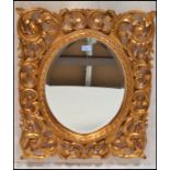 A large Florentine  style gilt wall mirror, the central oval mirror panel set within an ornate