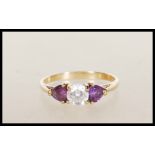 A stamped 375 9ct gold ladies dress ring set with a round cut CZ flanked with two heart cut purple