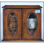 A mid 20th Century oak smokers cabinet having twin doors to the front with twin beveled glass panels