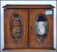 A mid 20th Century oak smokers cabinet having twin doors to the front with twin beveled glass panels