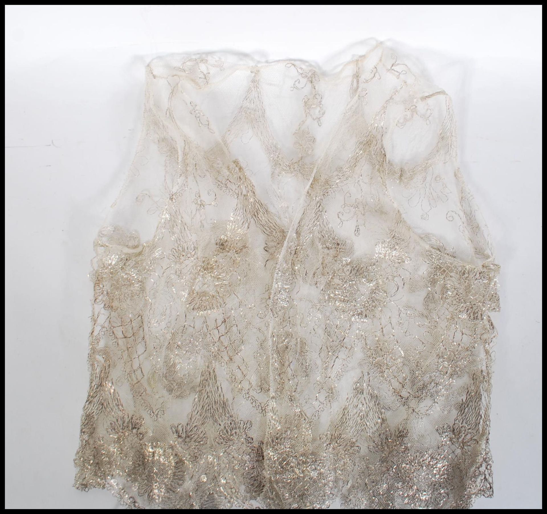An early 20th Century Edwardian ladies lace waistcoat of small proportions, having silver woven