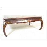 A 20th Century Chinese lacquered burgundy opium table / coffee table raised on bowed legs with