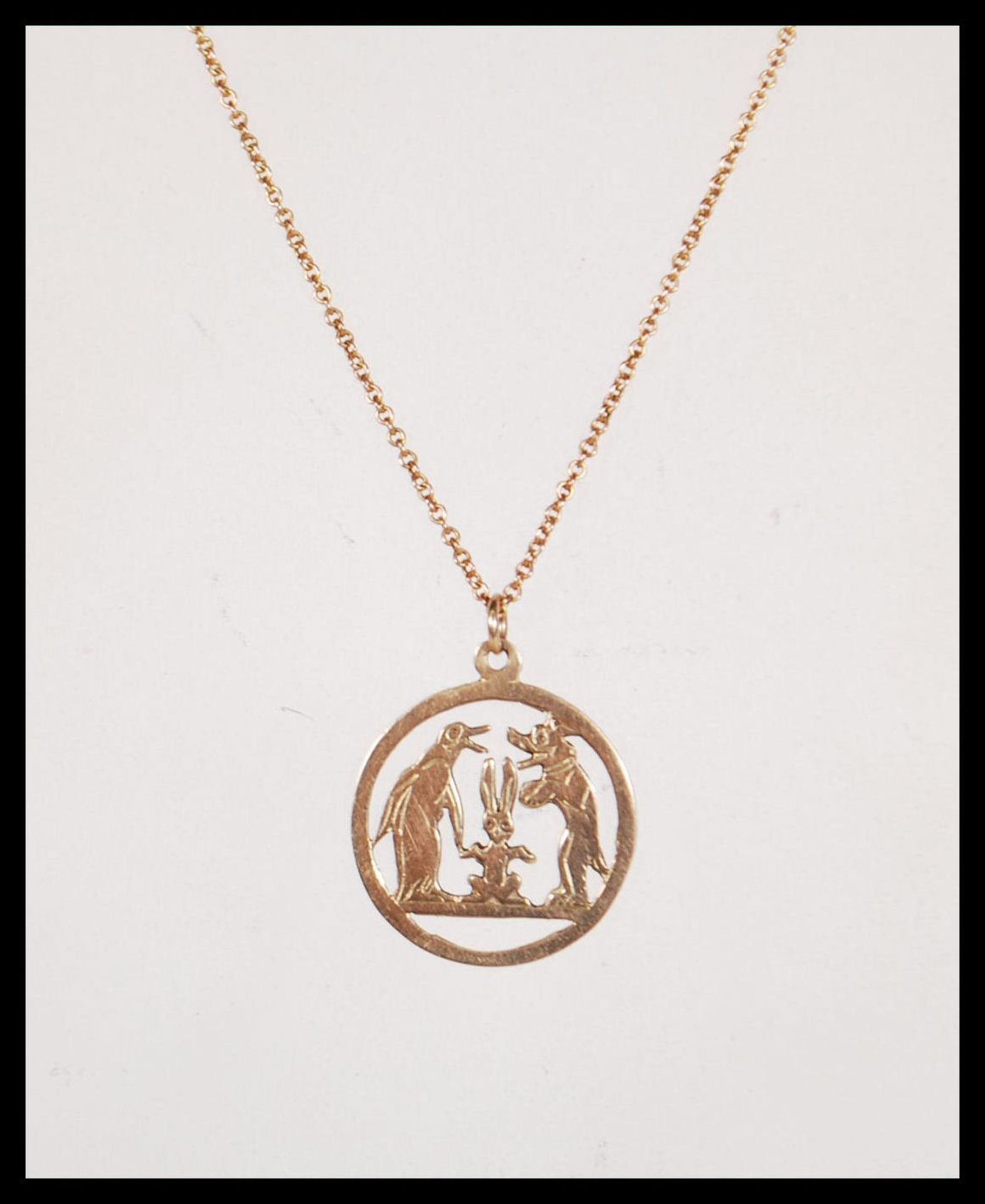 A stamped 9ct gold necklace having a round pendant having pierced decoration in the form of a dog,